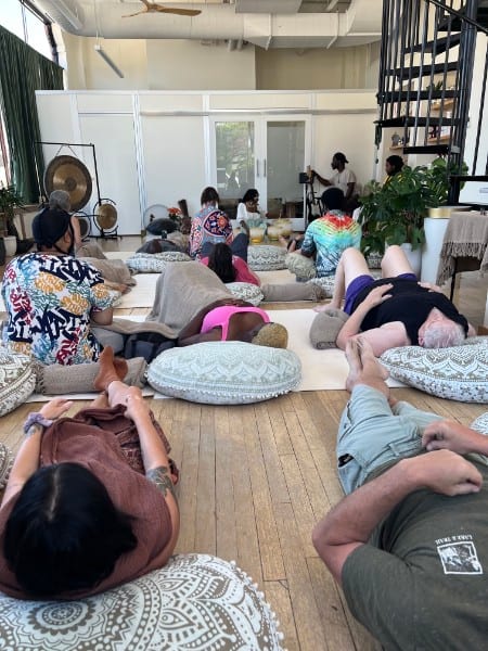Community sound bath at Hive Holistic Center, guests resting on floor cushions around a gong